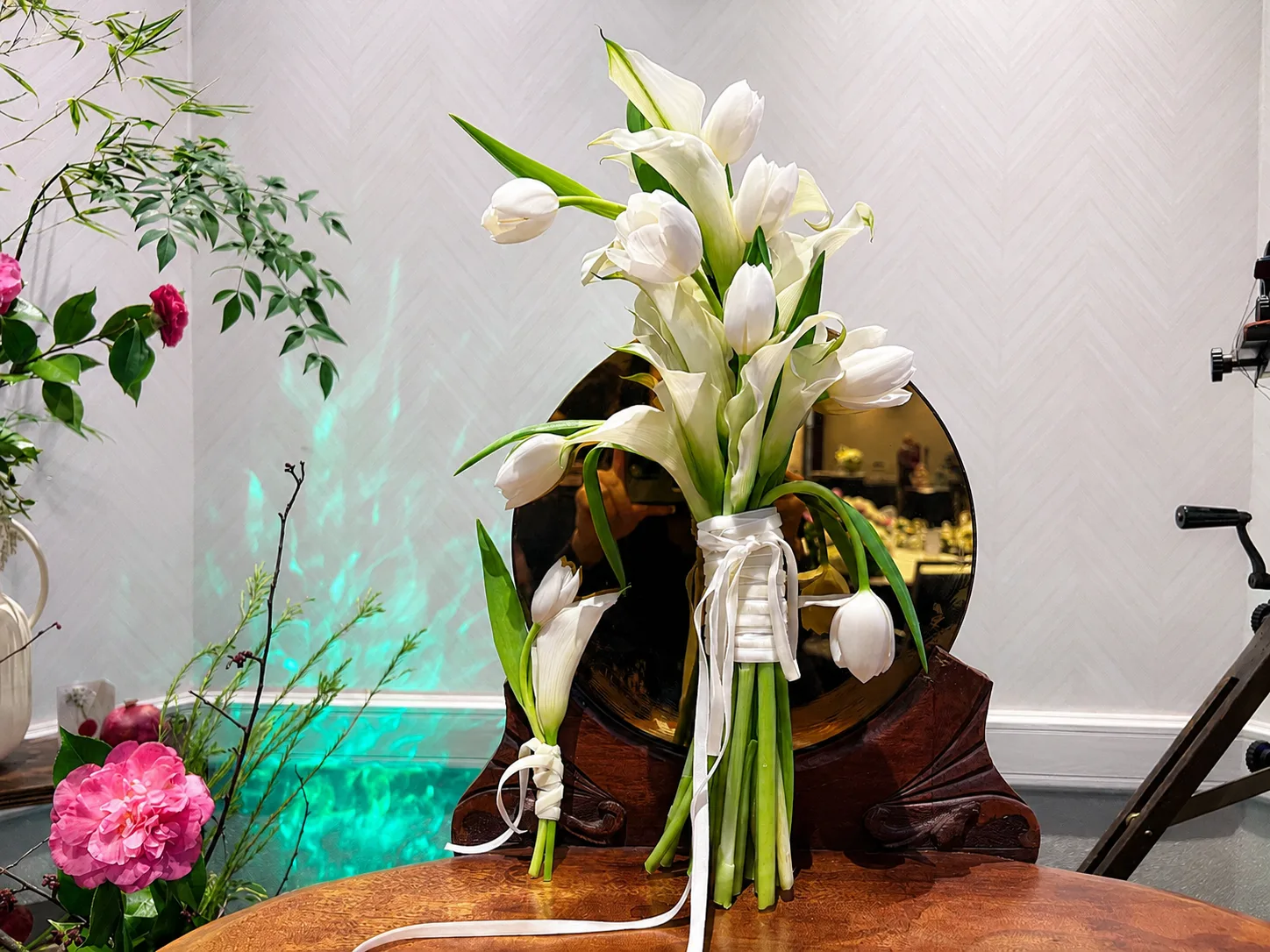 White tulip and calla lily bouquets tied with ribbon, resting against an antique mirrored vanity